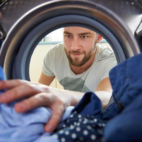 man is taking out clothes from washing machine