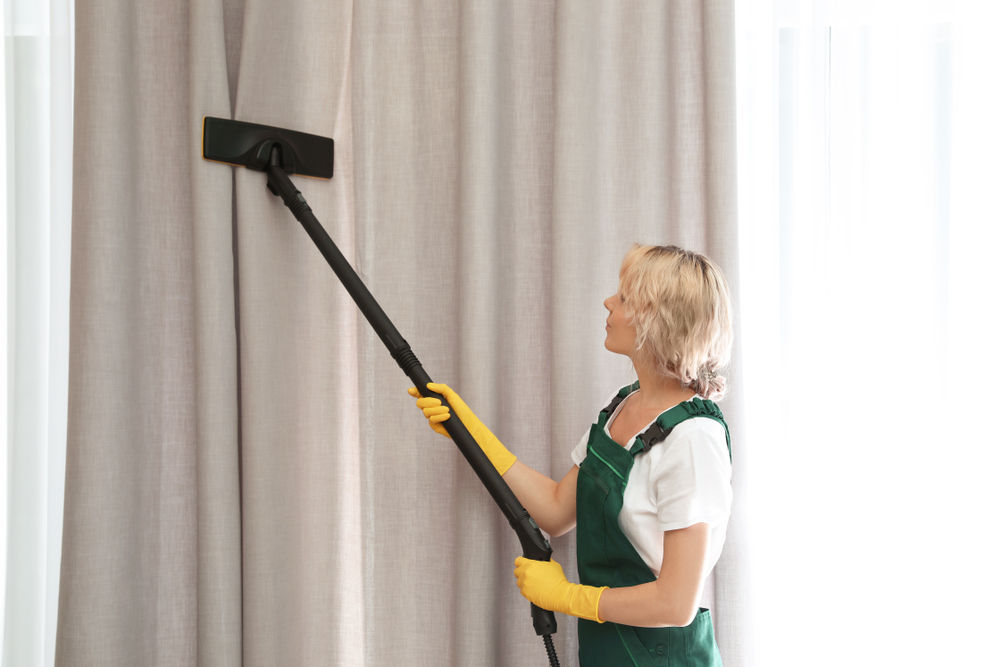 A lady is cleaning the curtain